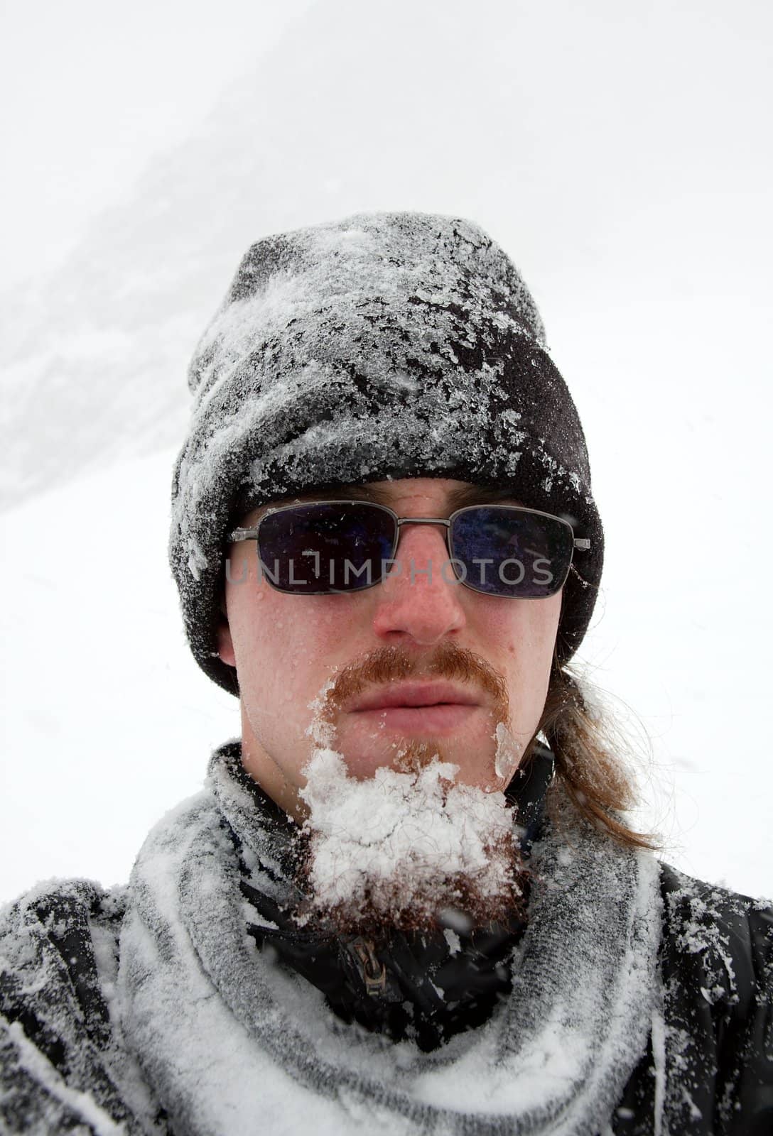 Portrait of a bearded man cover by snow in a blizzard