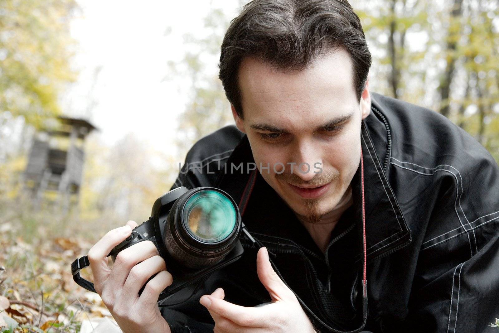 Photographer with his camera looking at the ground outdoors