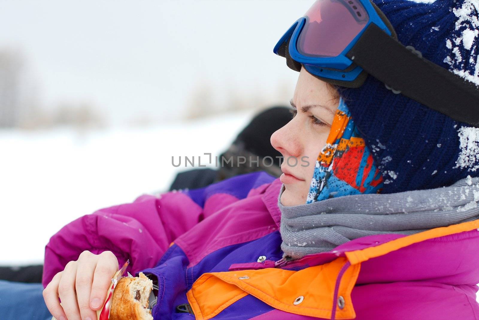 Young, female skier relaxing and eating