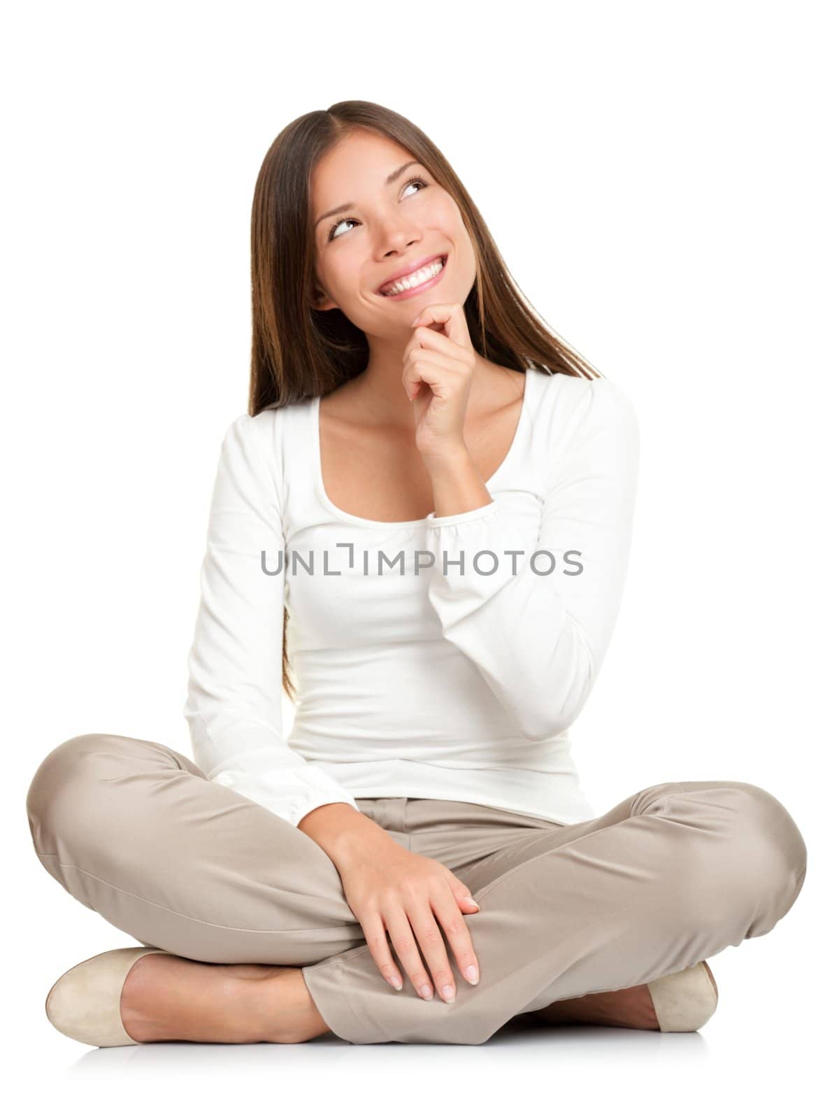 Thinking woman sitting on floor isolated on white background. Beautiful young mixed race Caucasian / Asian female model smiling looking up.