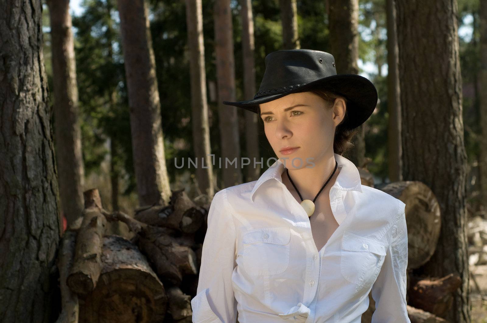 Portrait of a woman in a white shirt and cowboy hat on a ranch.