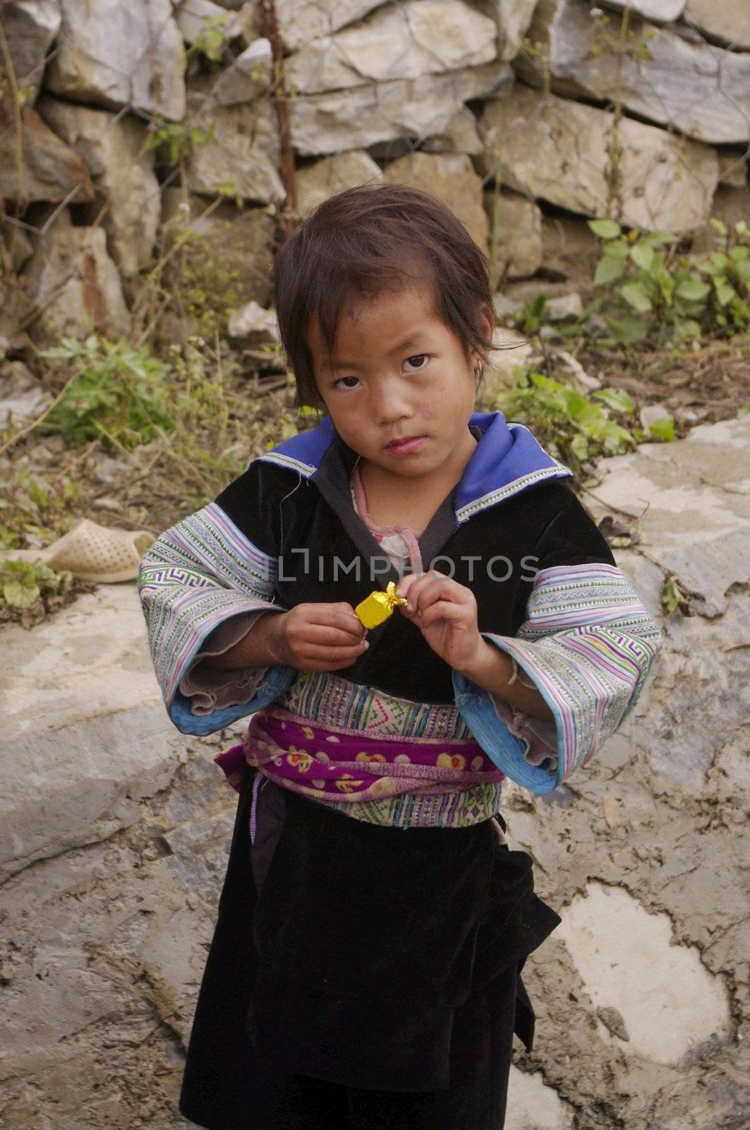 Portrait of a child of Hmong traditional dress in blue. 
It is no coincidence, or a party, but it's held every day. 
At the same moment his mother does the laundry in the gutter fed by water coming down the mountain.
