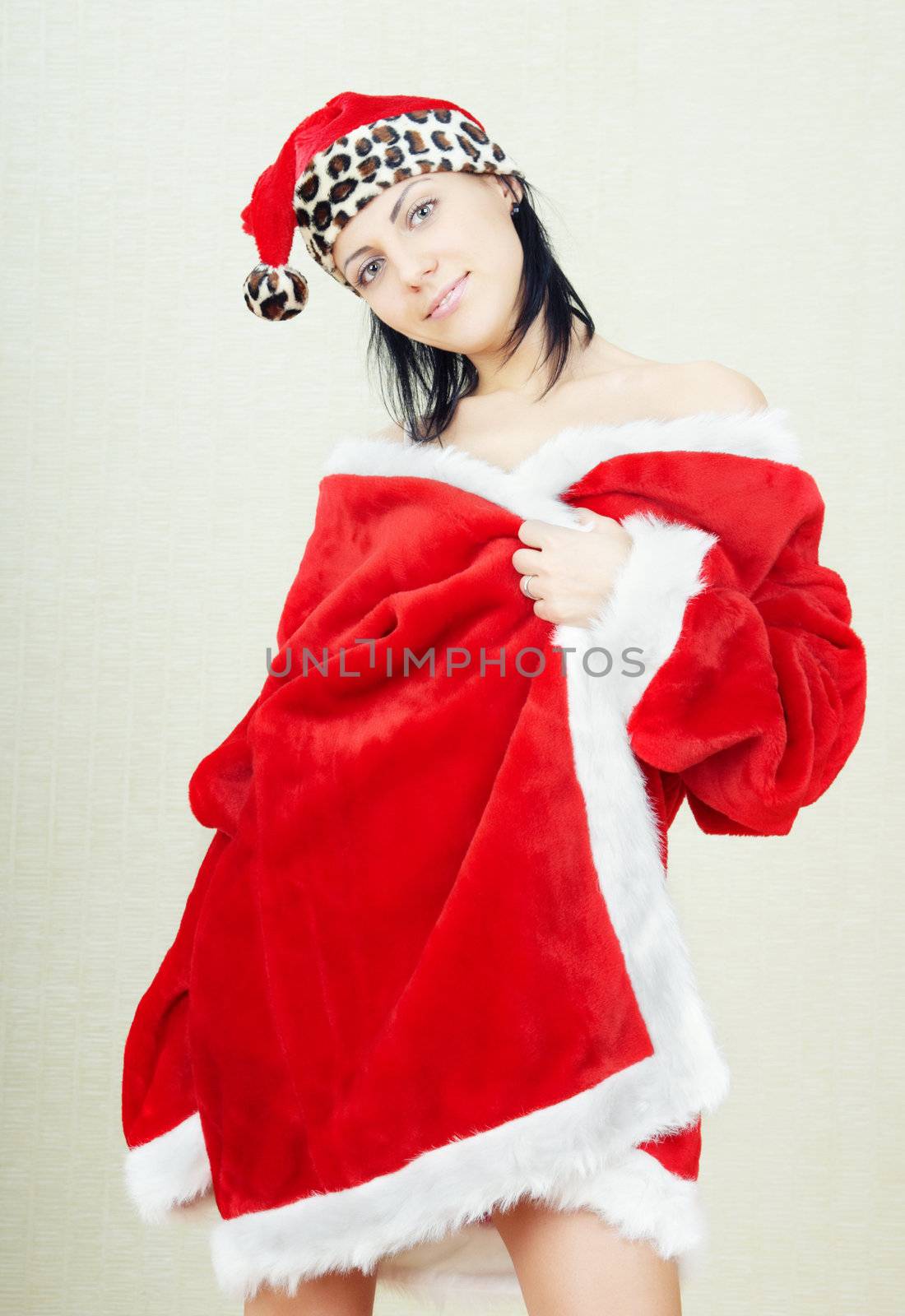 Smiling brunette lady indoors in the red furry Santa Claus dress and hat