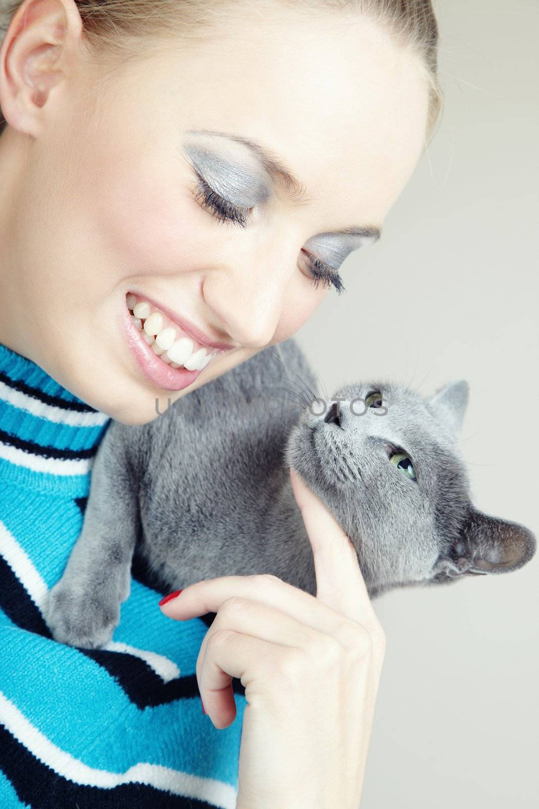 Smiling woman holding and pampering cat indoors