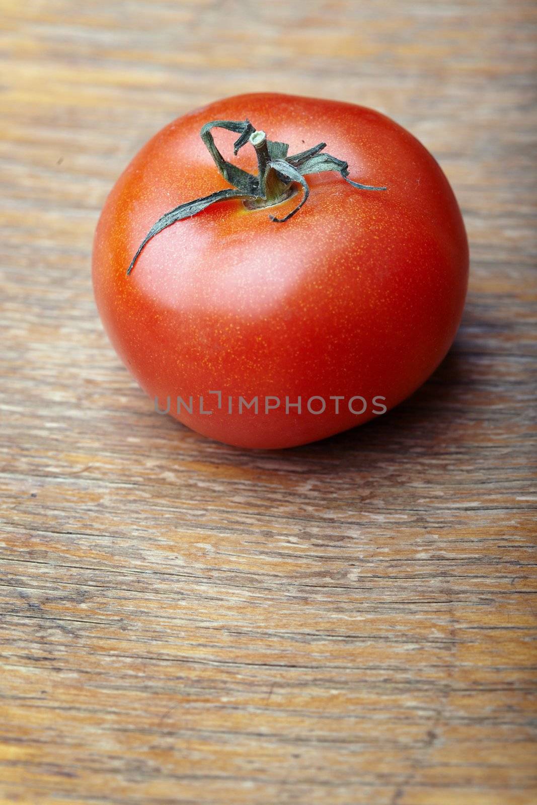 Close-up photo of the red tomato of the wooden background. Shallow depth of field added for natural view