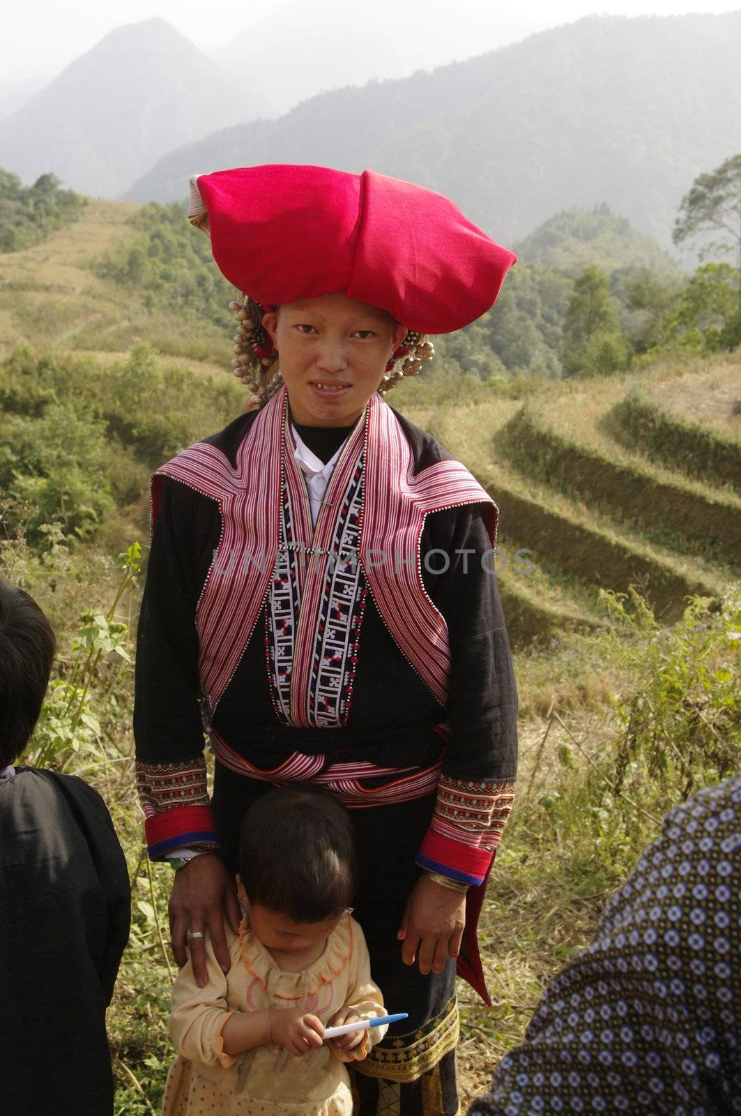 Woman of the ethnic (minority) Hmong red pompoms. This beautiful woman is the traditional clothing of his tribe and the headdress of married women. A basket in the back he used to transport vegetables to the house and contains the essential umbrella, which also serves to protect against the sun. The standard of beauty for women in Asia is to have white skin.