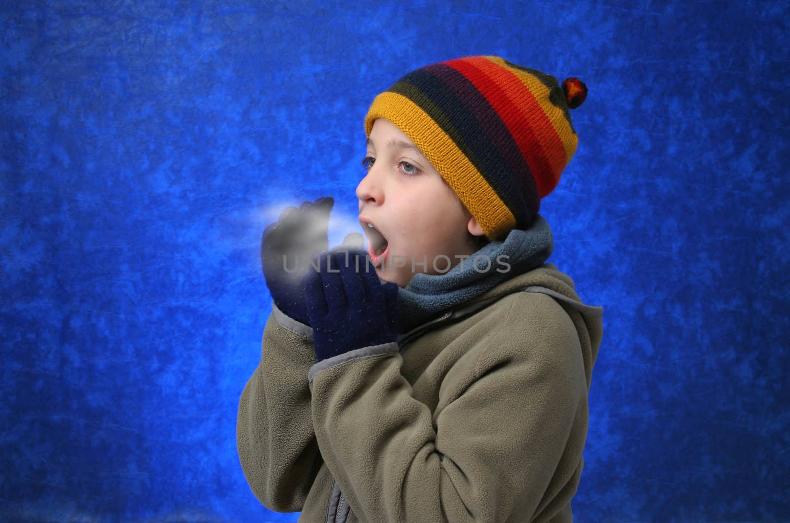 Child trying to warm his hands with his breath in winter outfit. Look at my gallery for more winter images
