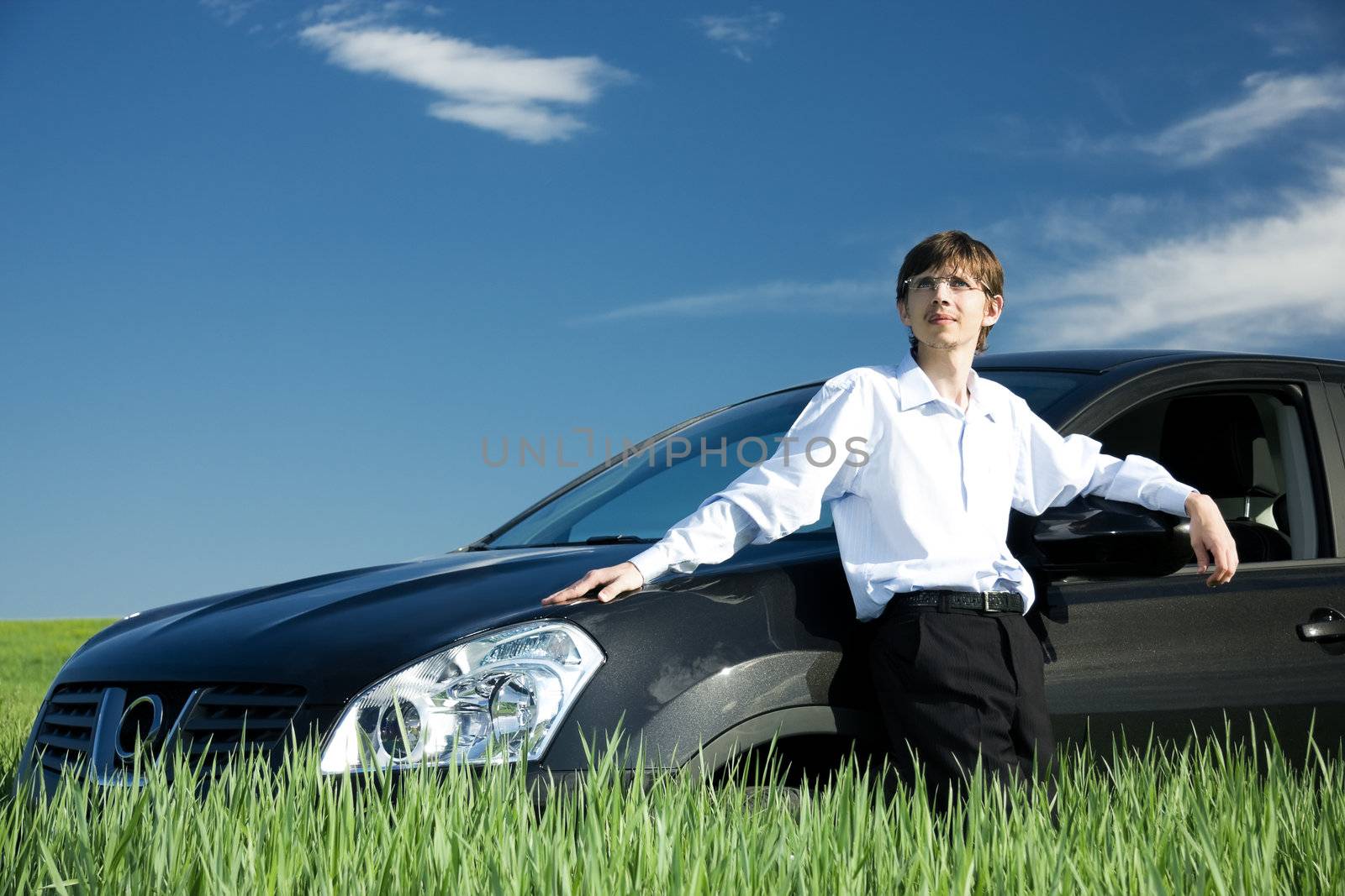 Successful businessman with car on grassland by rozhenyuk