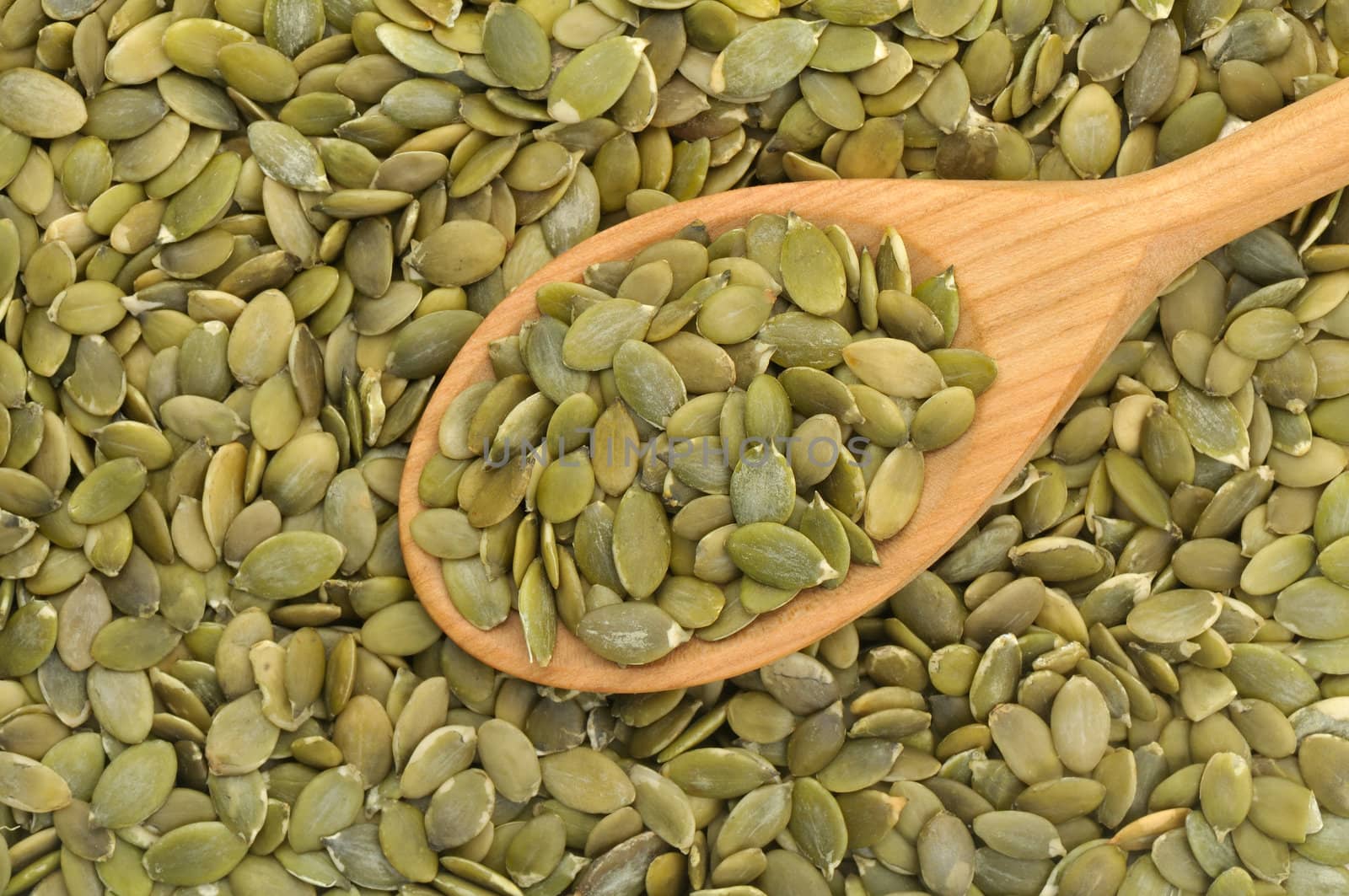 Wooden spoon filled with pumpkin seeds in natural light