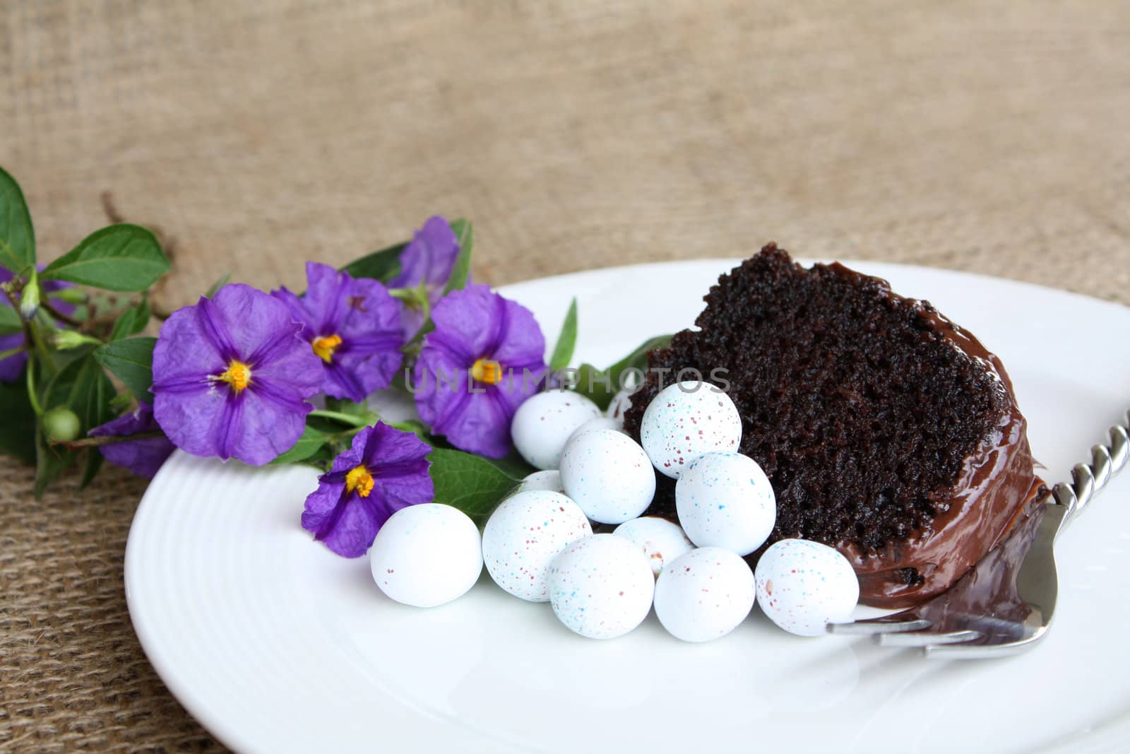 Sliced chocolate cake with mini easter eggs and flowers