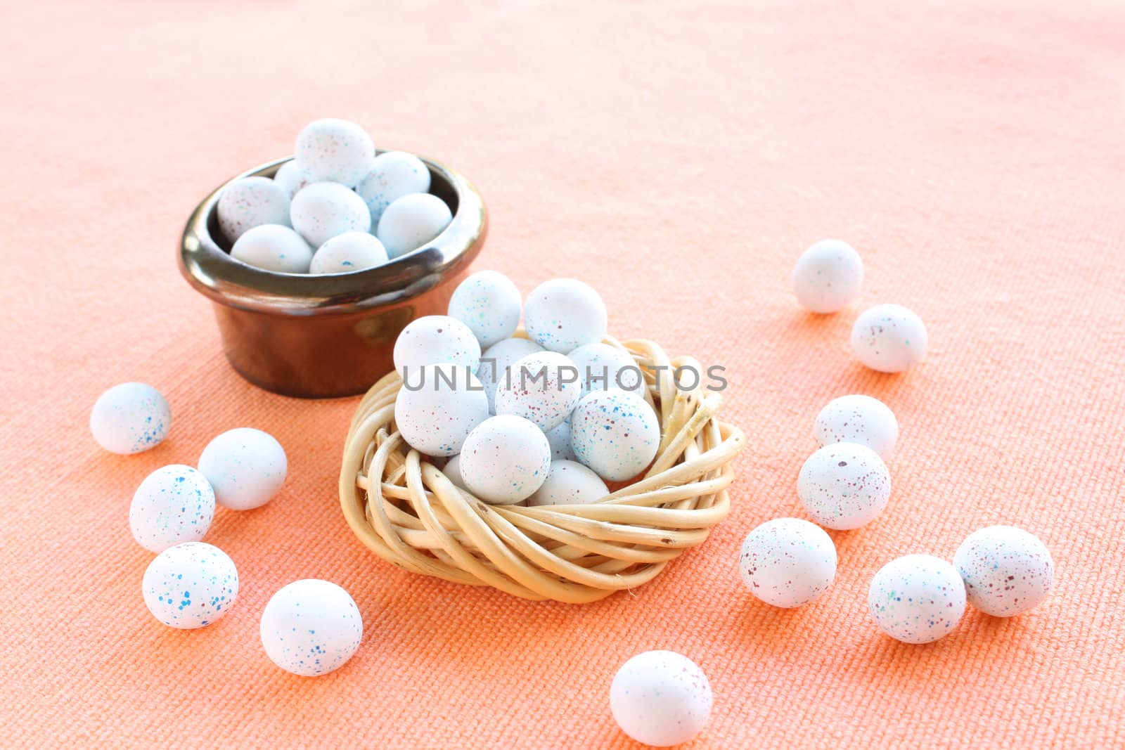 Miniature speckled easter eggs in two containers on an organce cloth