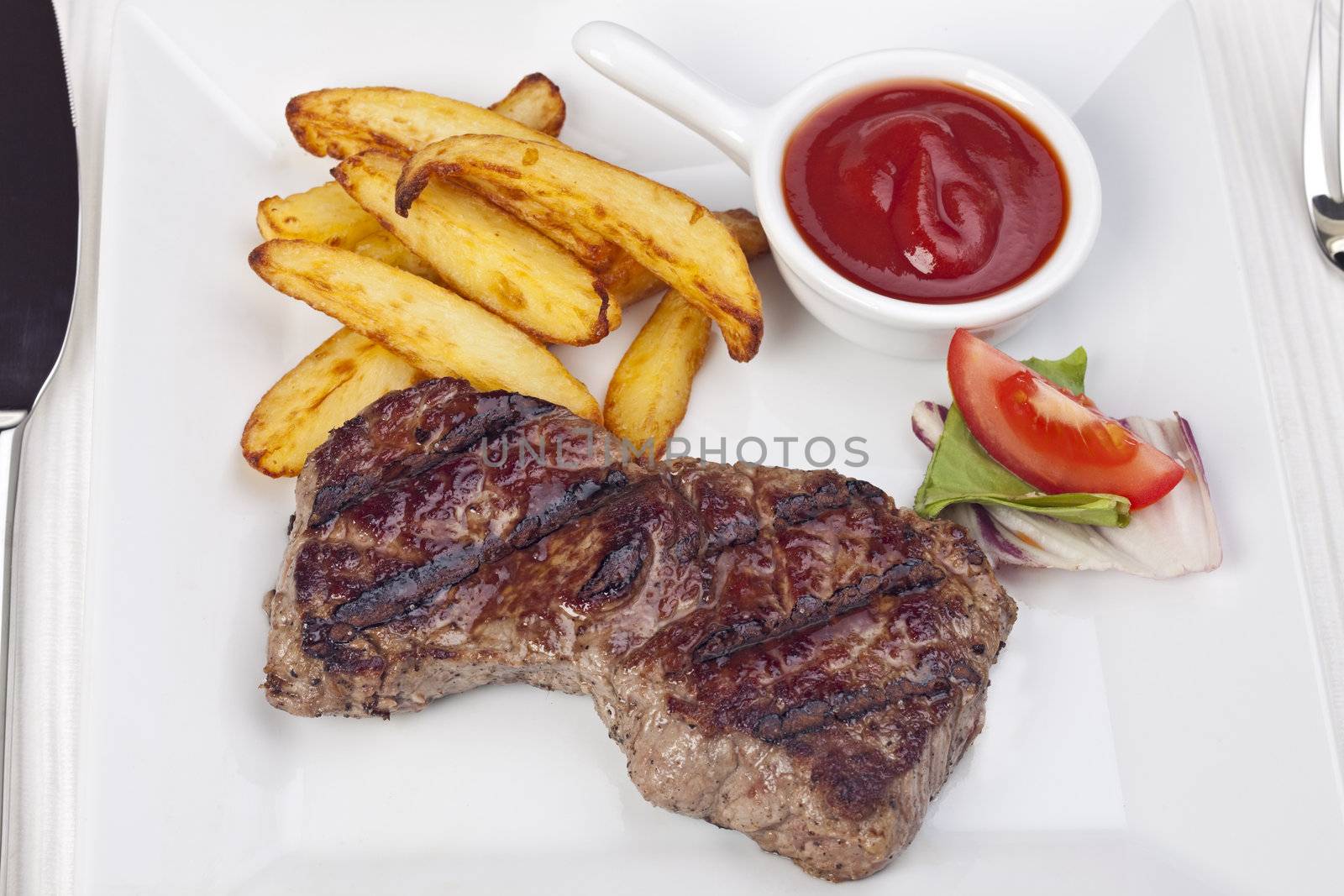 steak and french fries on a plate by bernjuer