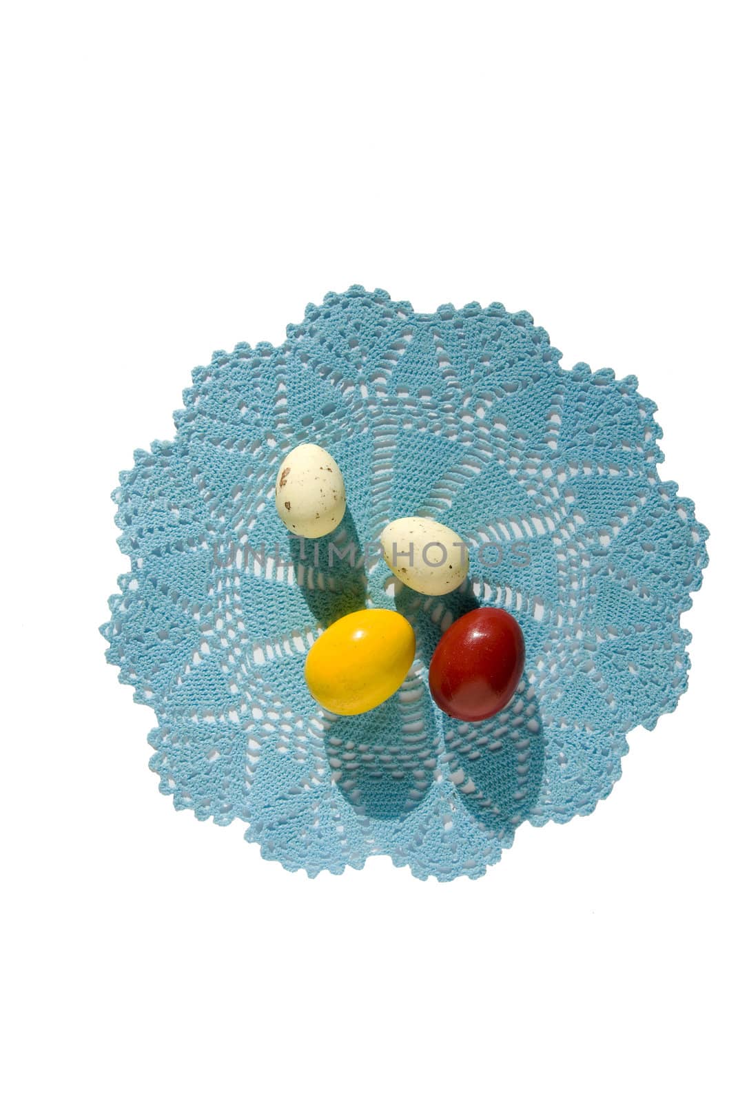 Four Easter eggs on a blue knitted napkin isolated on a white background