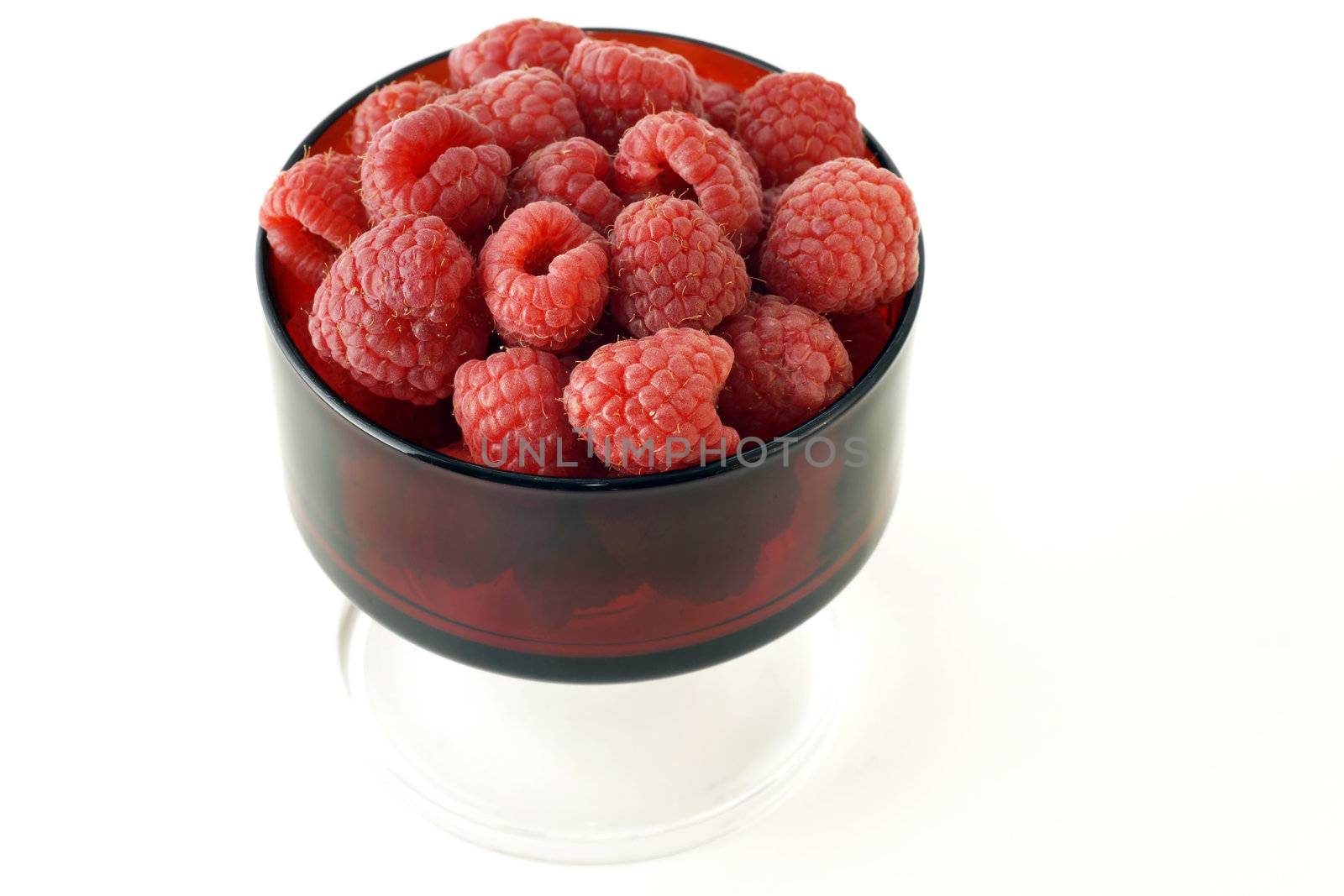 Vintage red glass filled with plumb raspberries, healthy and delicious fruits.