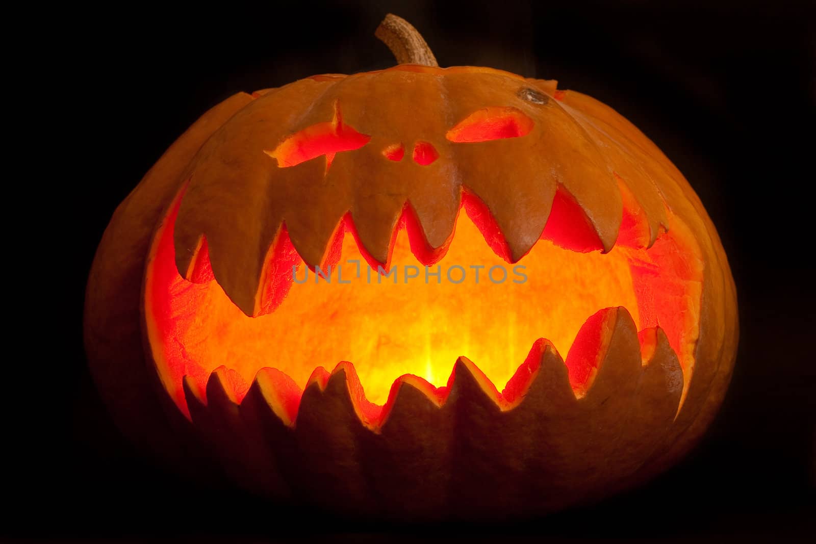 Wide carved pumpkin lit in the dark