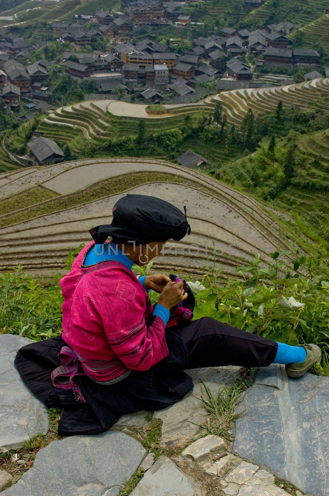 Woman sewing overlooking Longji Rice Terraces in Guangxi China