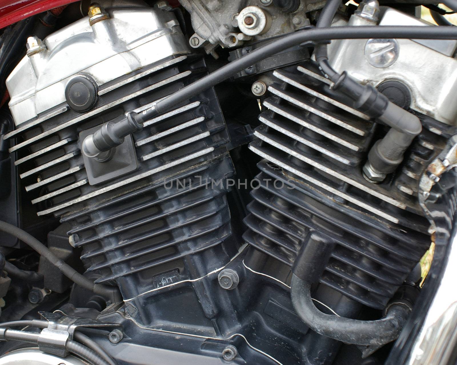 A closeup of a motorcycle engine showing cylinder heads and plug wires.