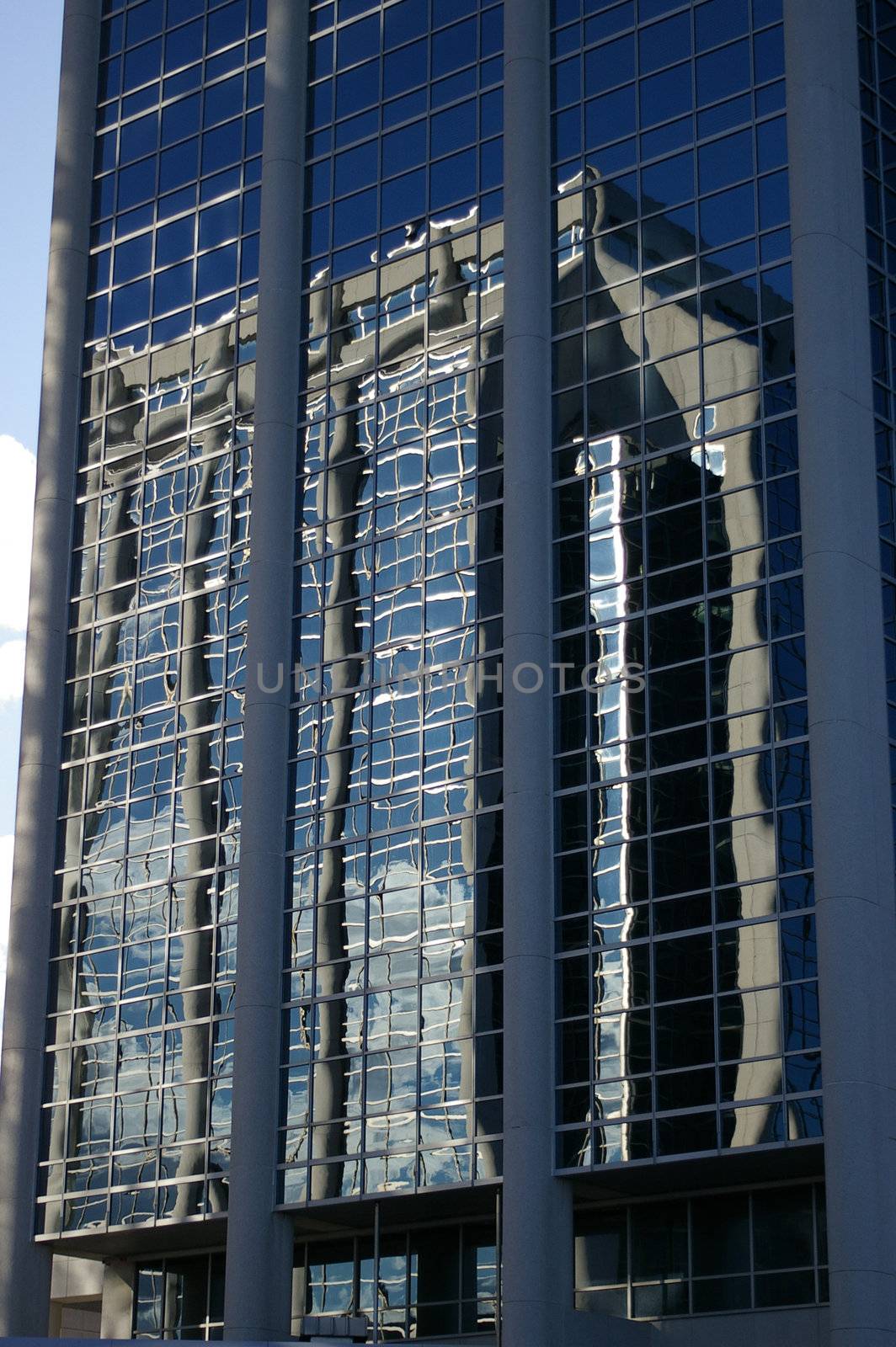 A concert and glass building reflected in another concert and glass building.