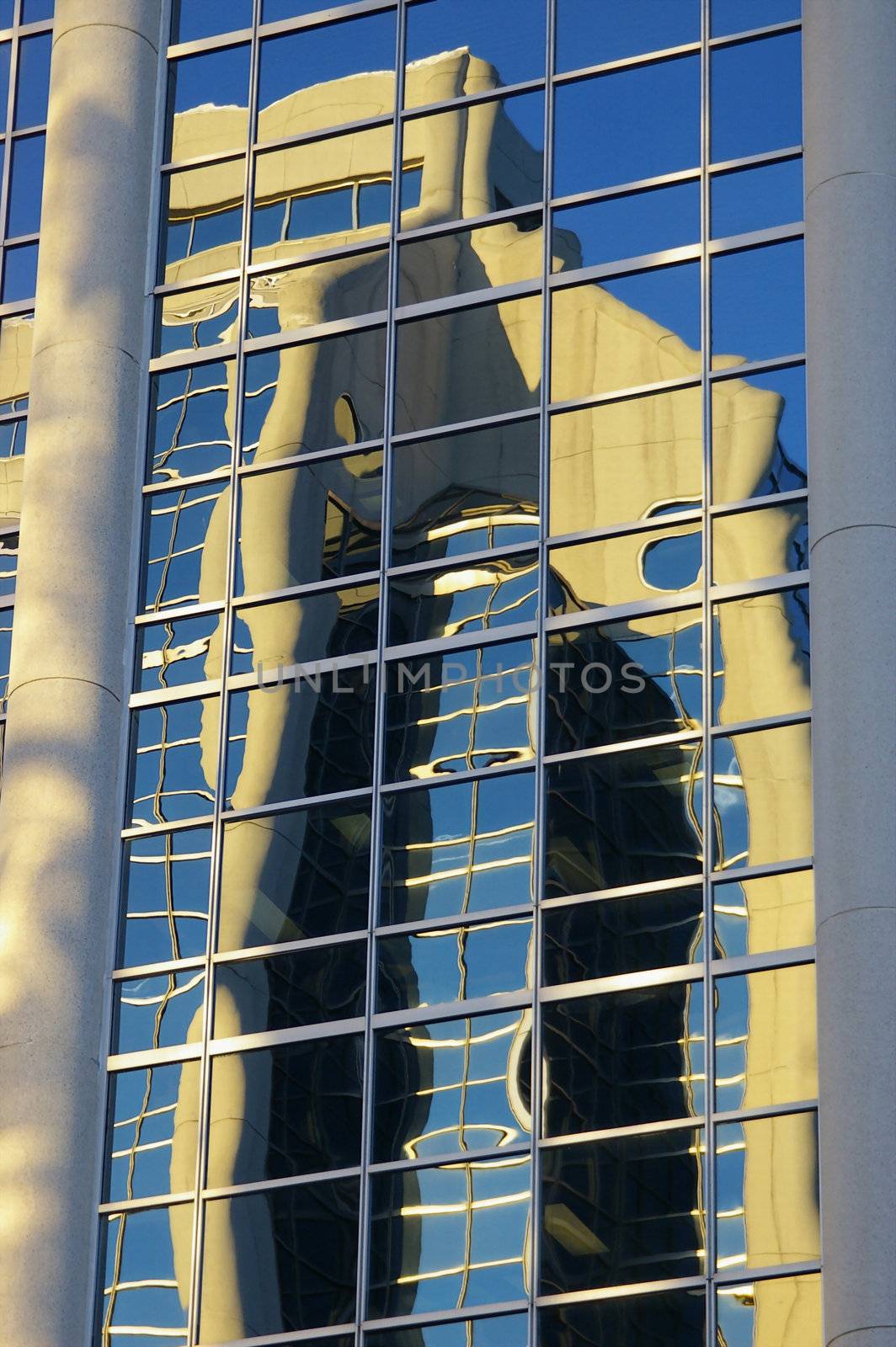 A concert and glass building reflected in another concert and glass building.