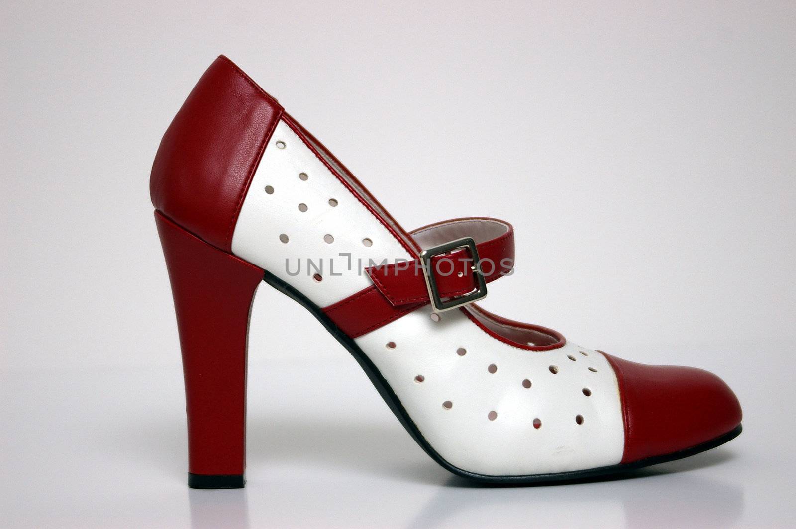 A side view of a red and white high heel on white.