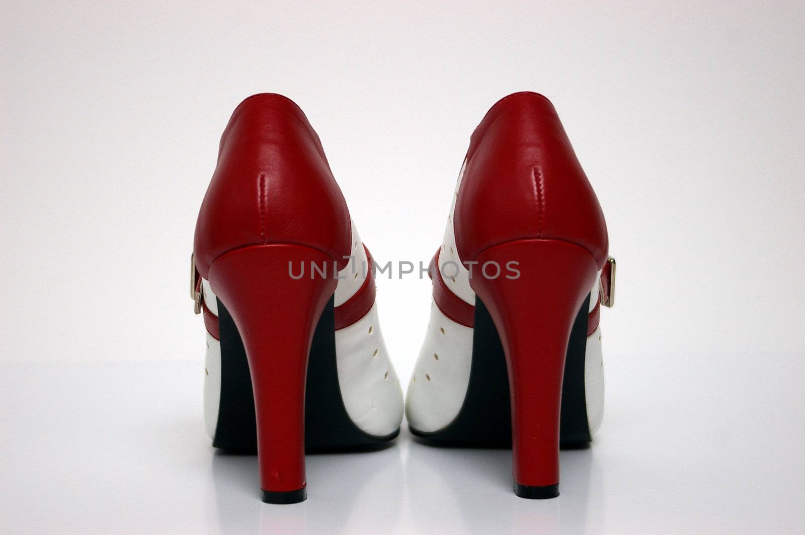 An end view of a red and white high heel on white.