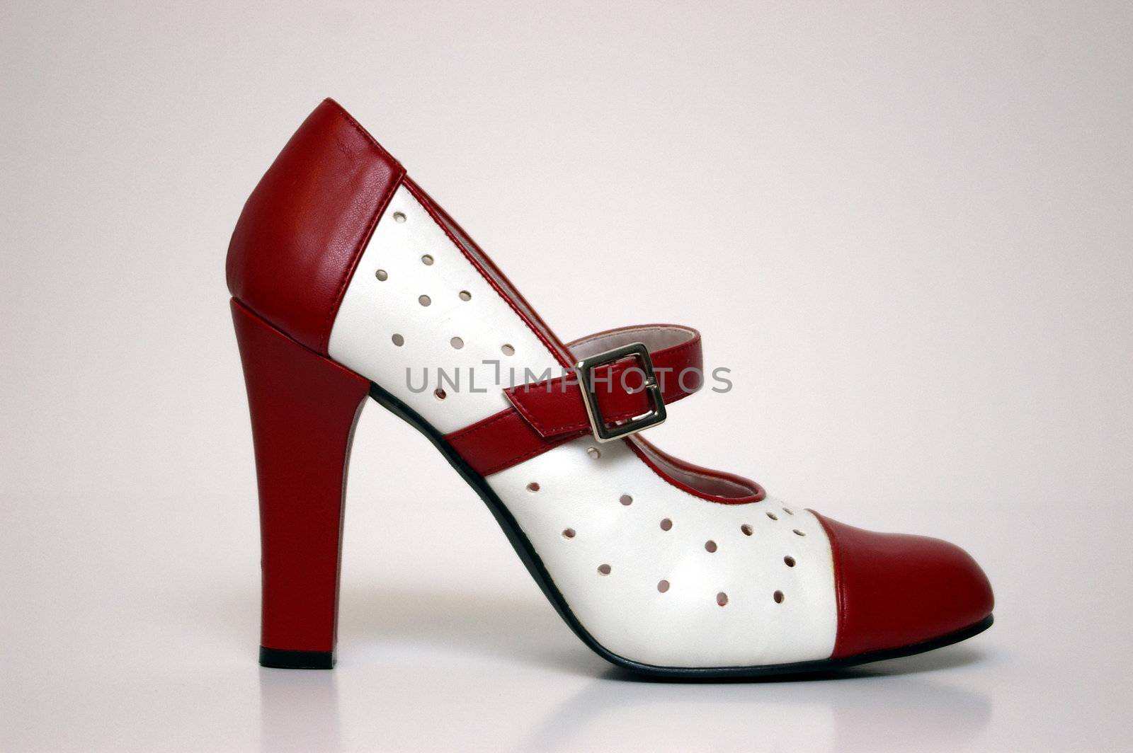 A side view of a red and white high heel on white.