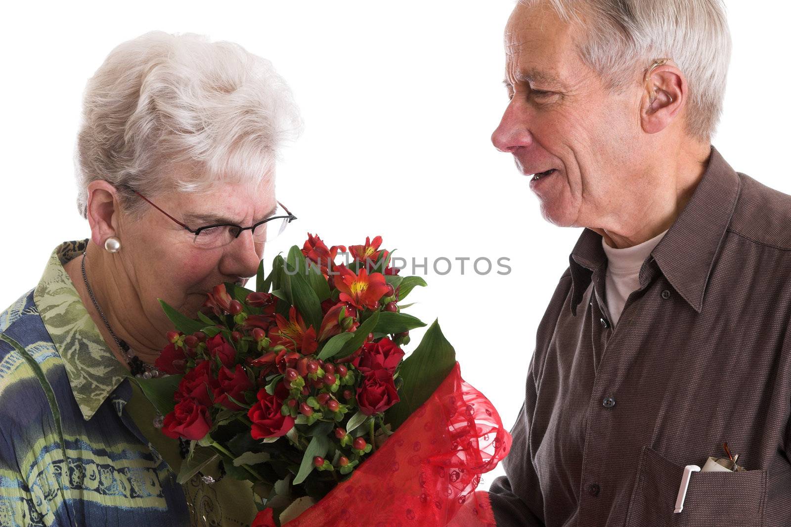 Senior couple where the woman is smelling the flowers that she has just received for valentines day