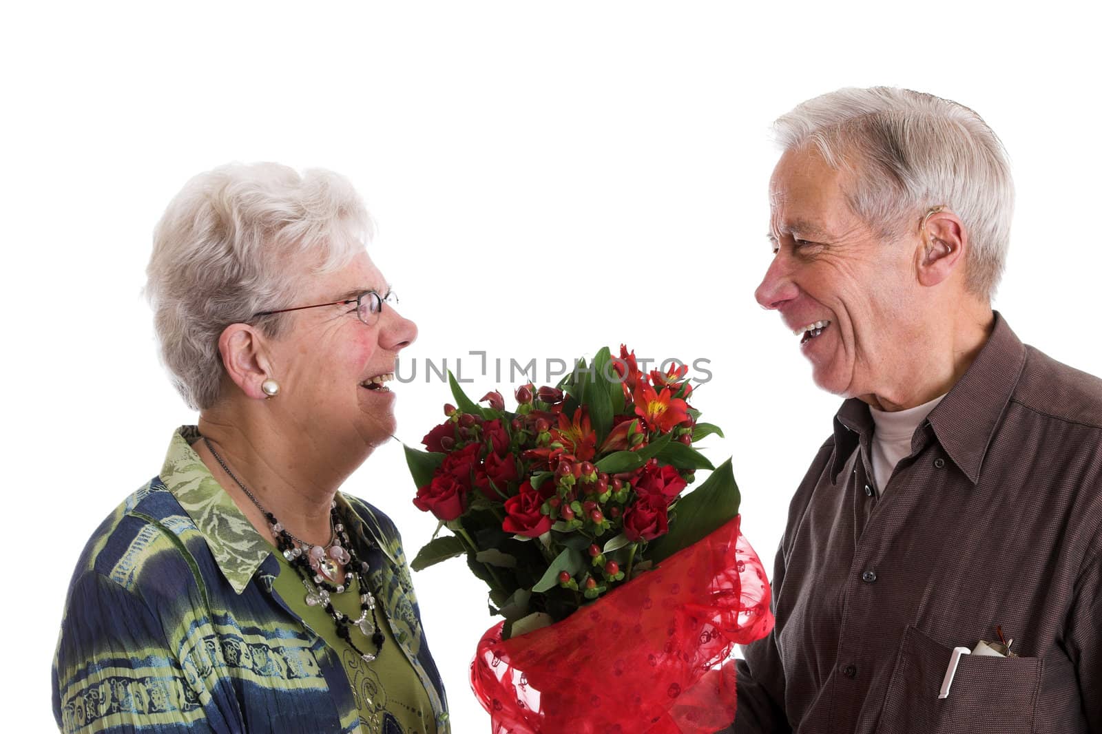 Cute elderly couple during valentines day; the man is giving his wife flowers