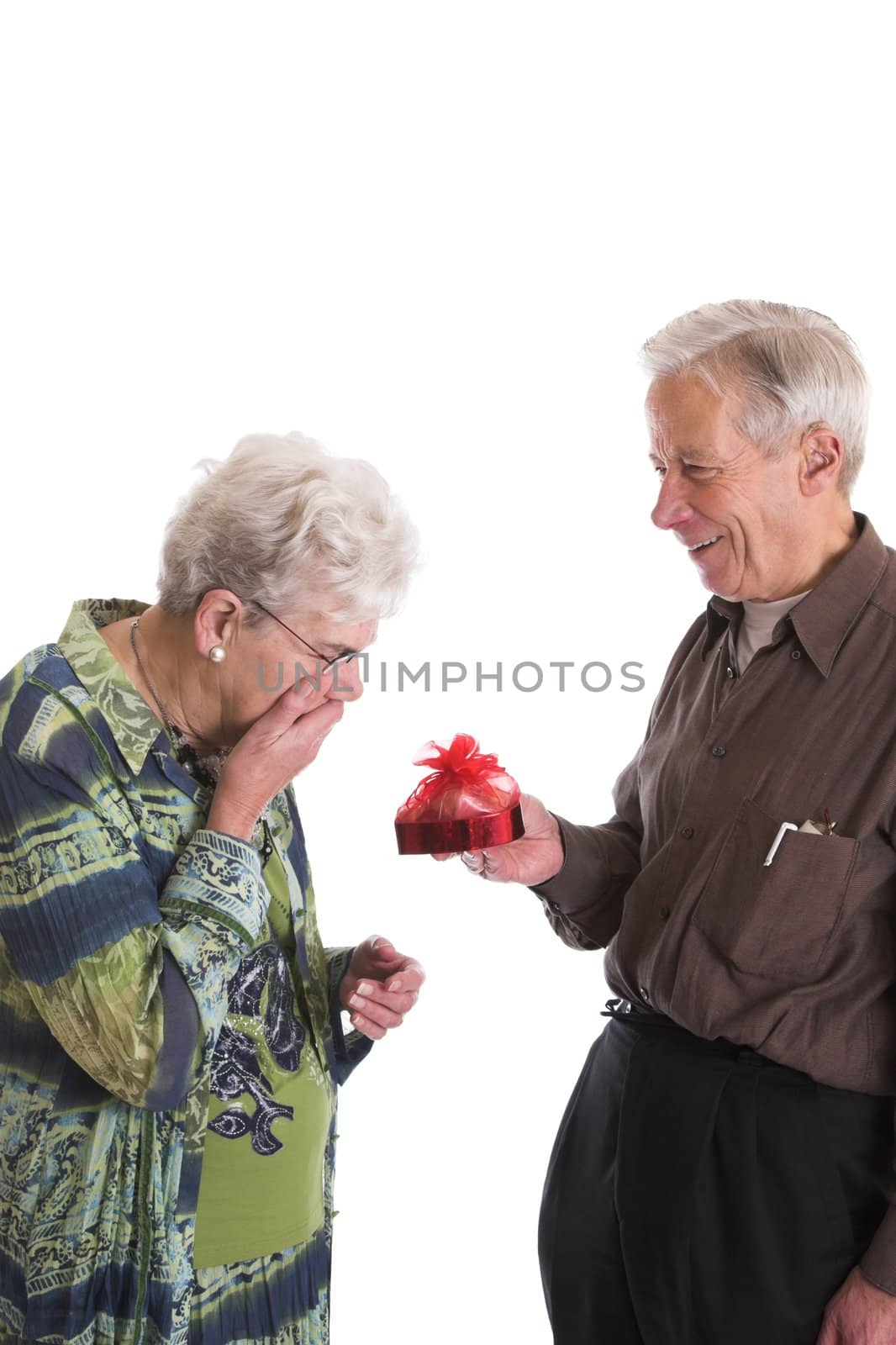 Elderly couple celebrating valentine; man is giving his wife a box of chocolates
