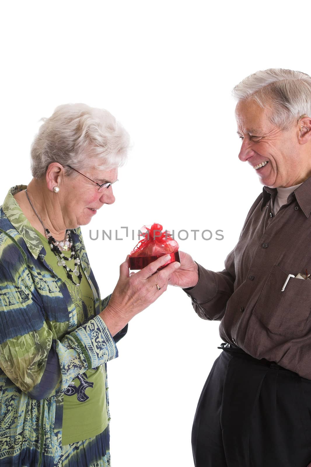Elderly couple sharing a fun moment when the husband gives his wife a box of valentine chocolates