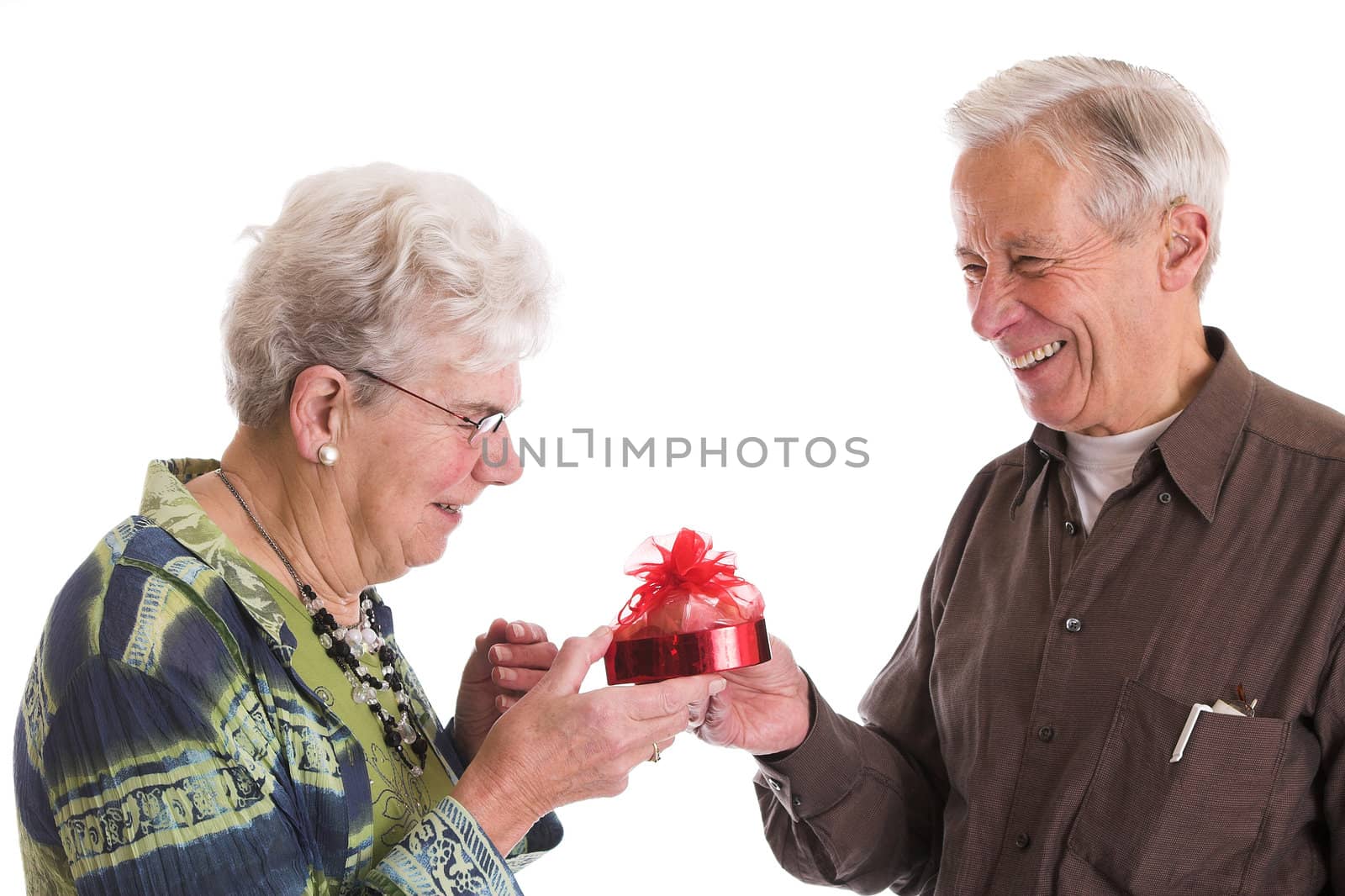 Cute elderly couple having fun together when the husband gives his wife a box of chocolate for valentines day