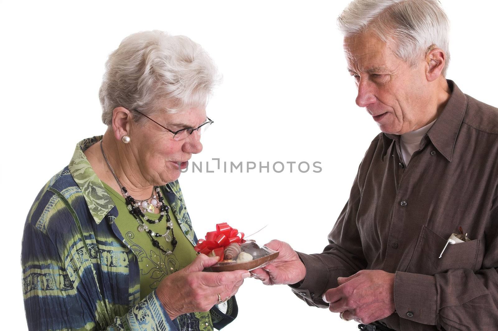 Elderly man giving his wife a chocolate heart filled with more chocolates for valentines day