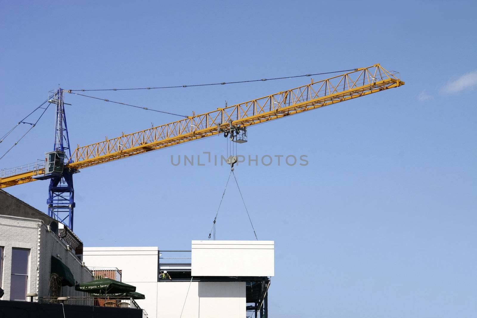 large crane lowering a large slab of concrete onto the side of a building construction