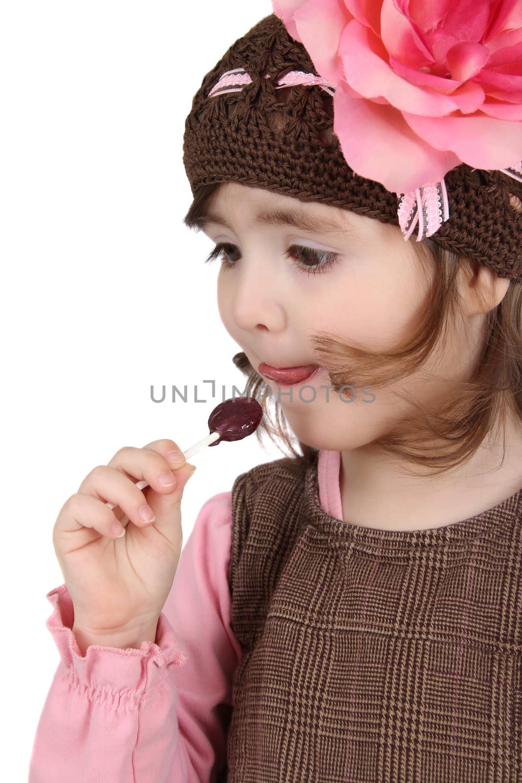Cute brunette toddler earing a lollipop against white background