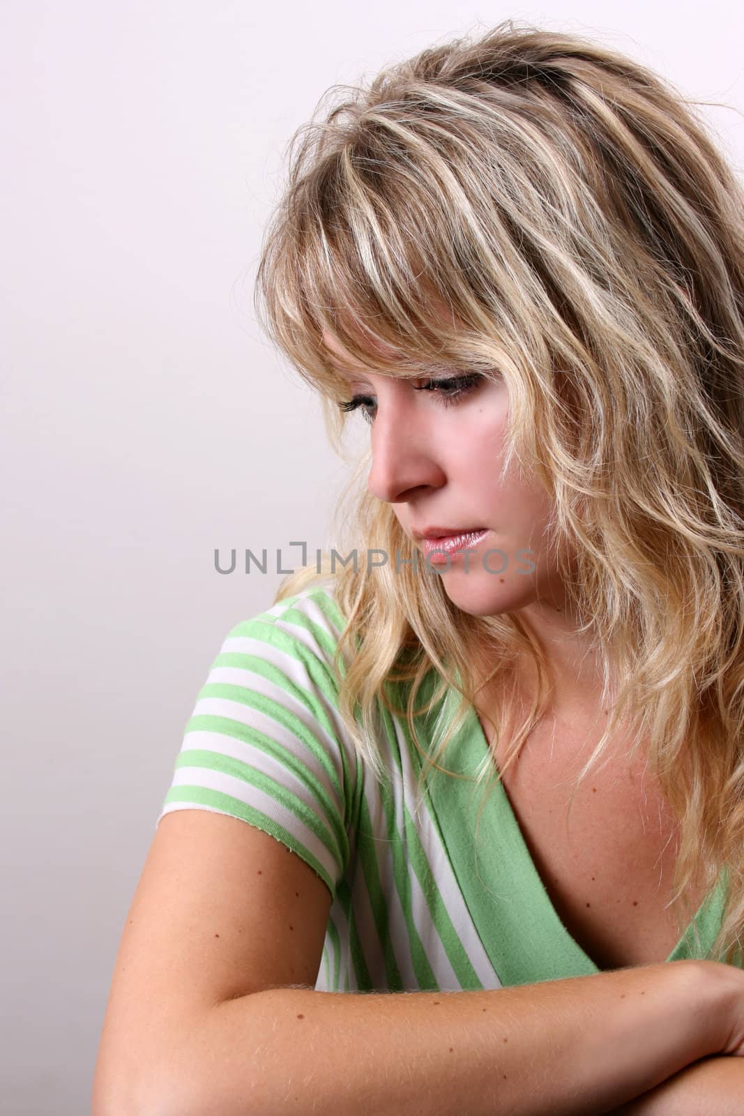 Blond Female model on a white background wearing a green top
