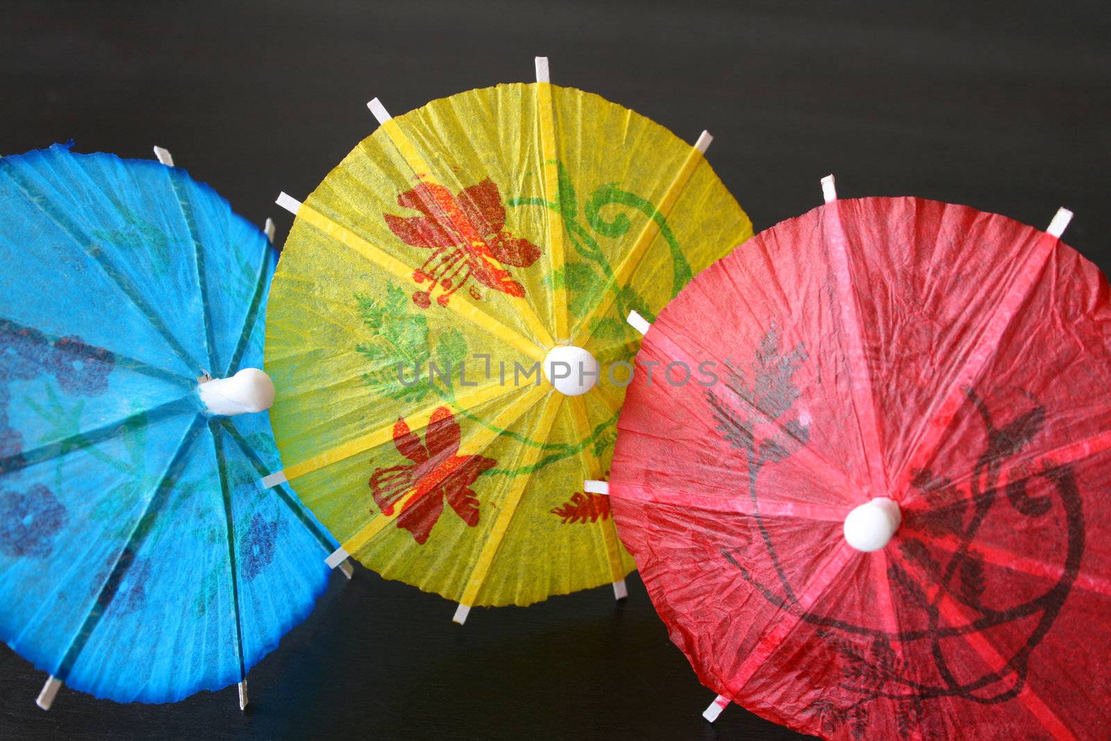 Blue, yellow and red Cocktail Umbrellas on a dark surface