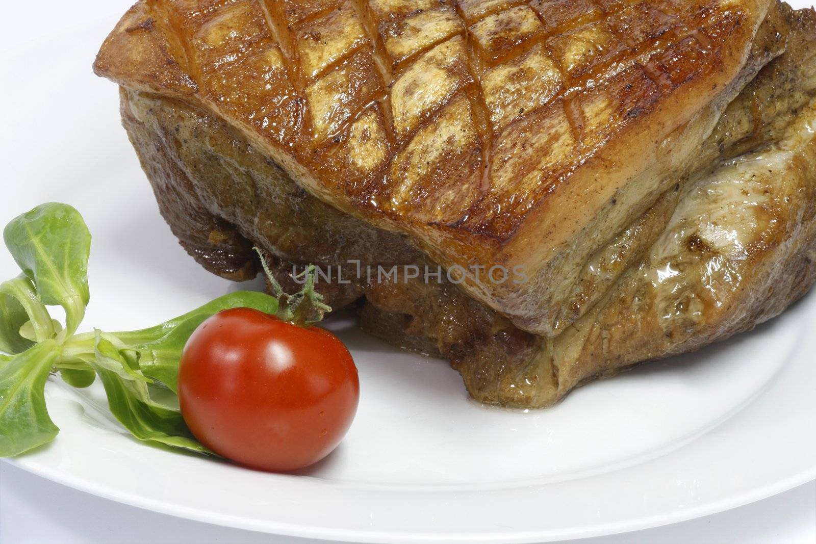 Crunchy pork roast on a plate over white background