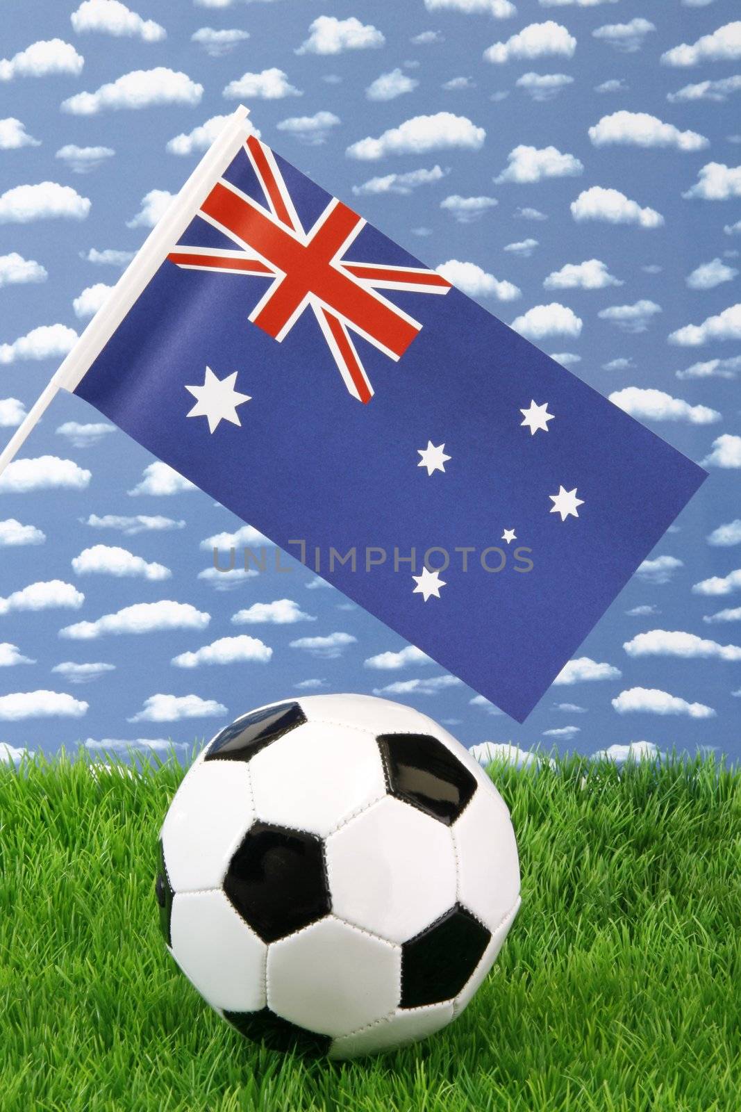 Soccerball on grass with australian national flag over sky background