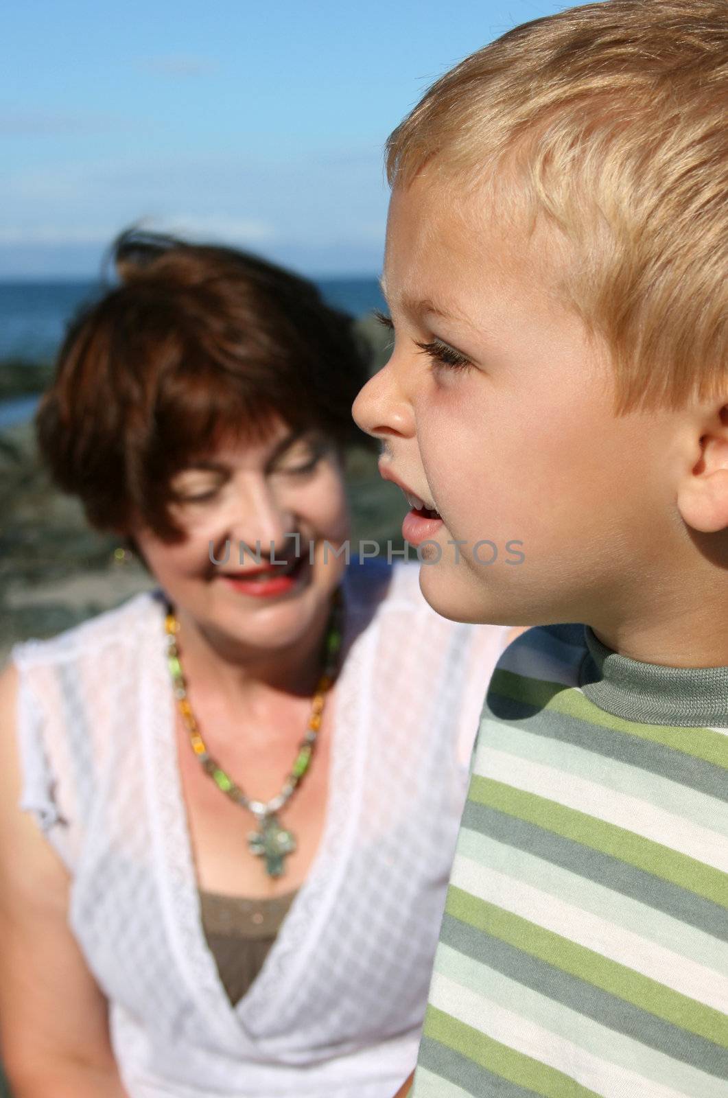 Beatiful grandmother and grandson playing on the beach