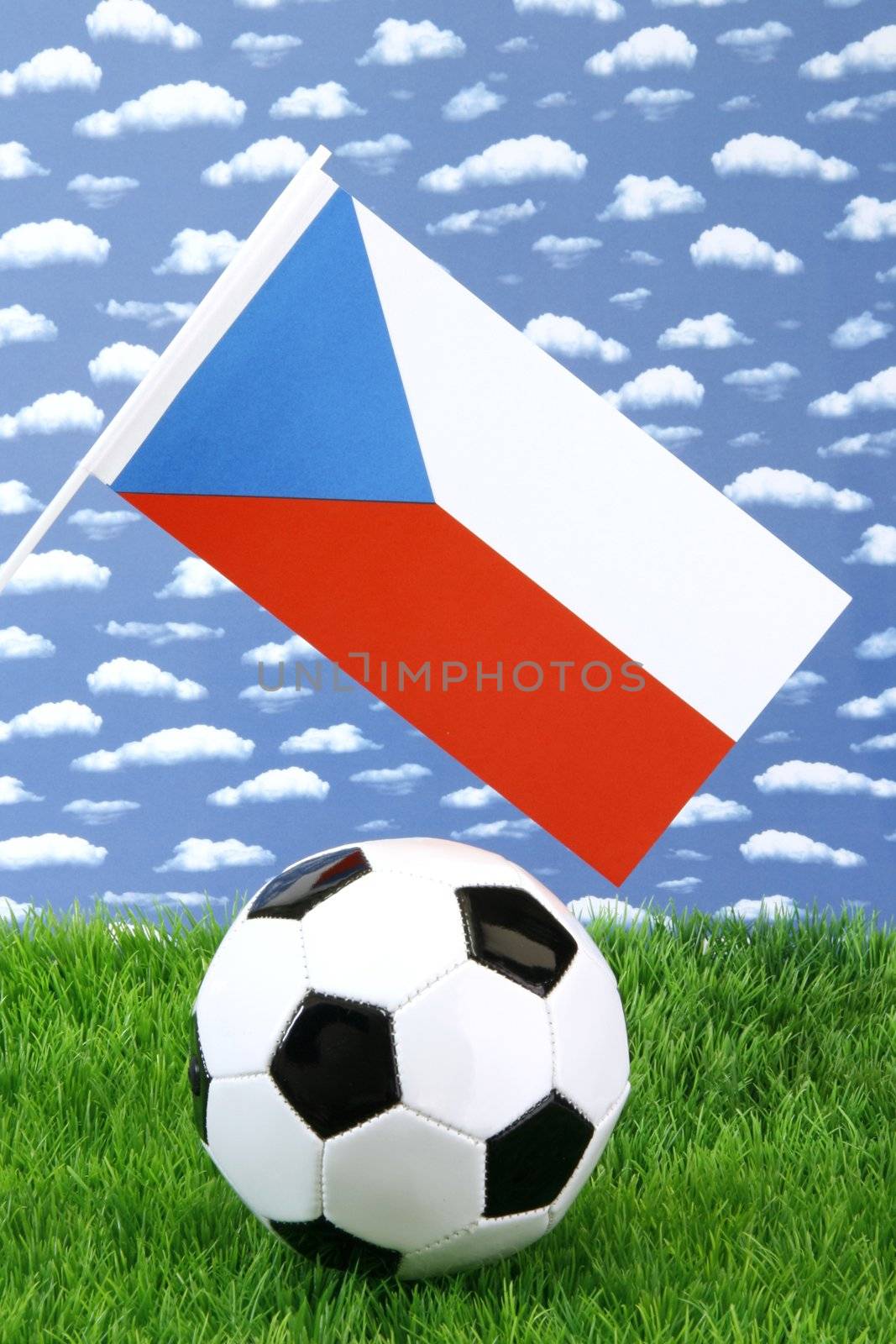 Soccerball on grass with czech national flag over sky background