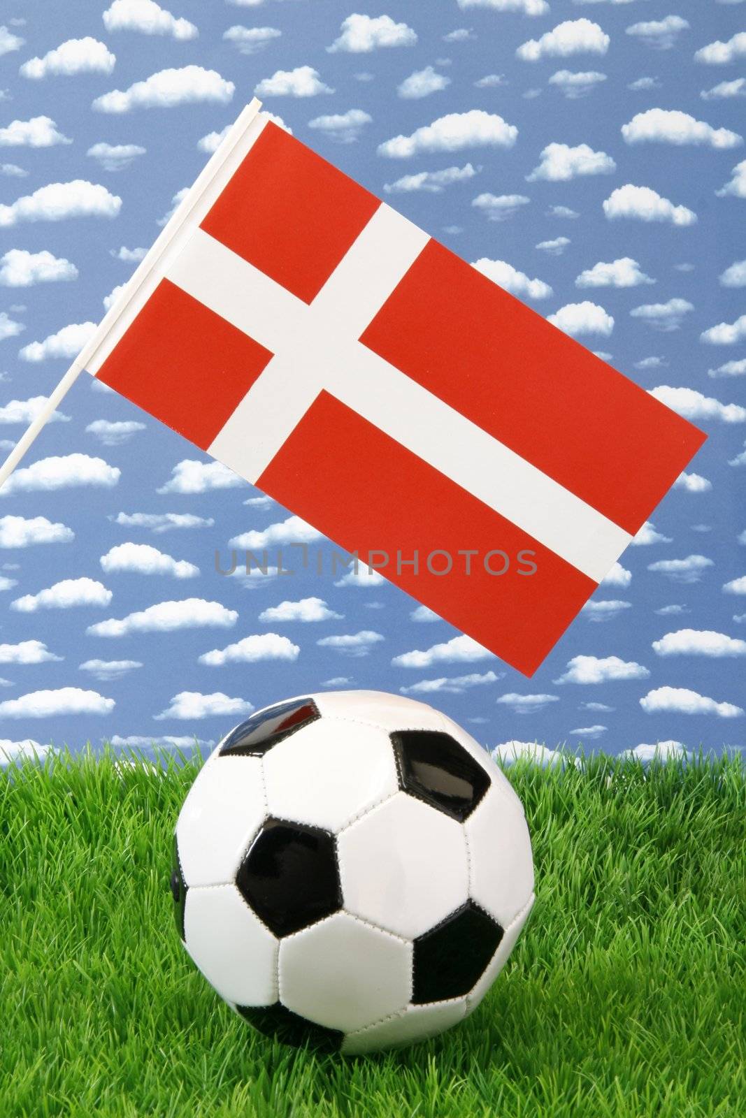 Soccerball on grass with danish national flag over sky background