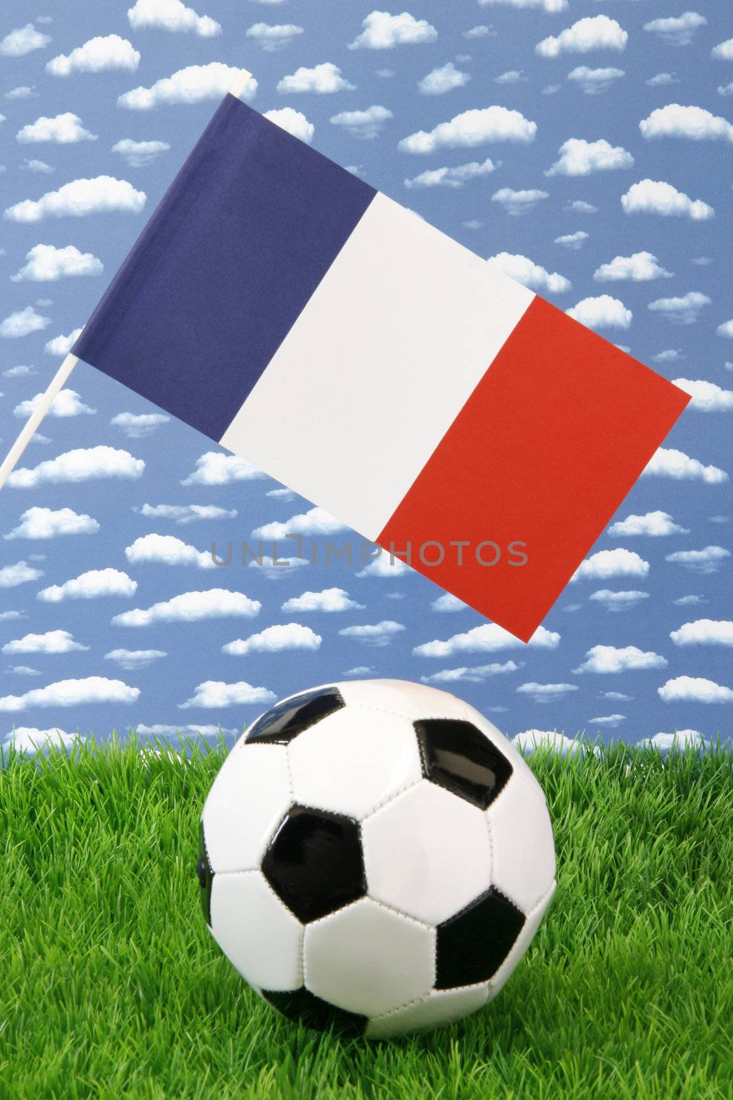 Soccerball on grass with french national flag over sky background