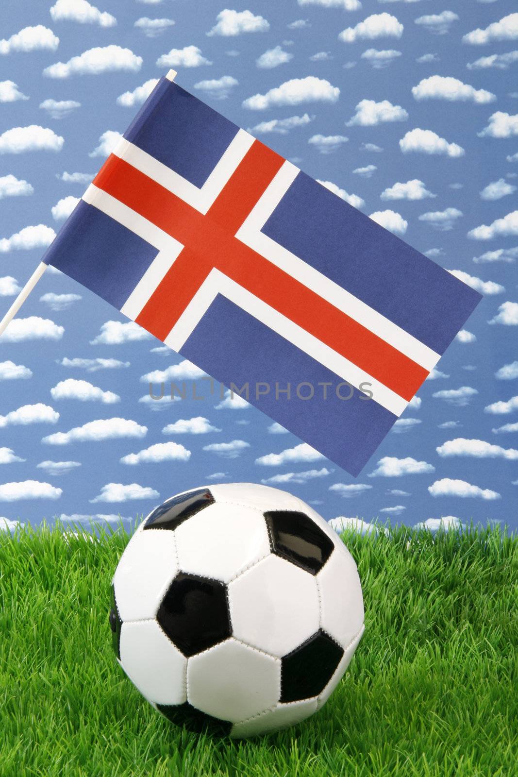 Soccerball on grass with icelandic national flag over sky background
