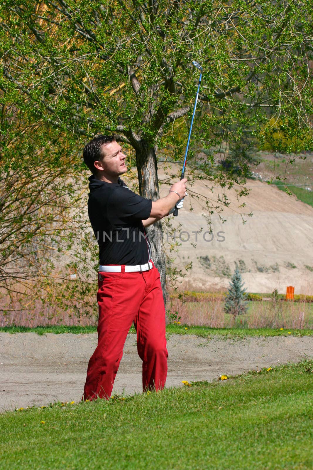 Young male golfer playing a shot from the bunker