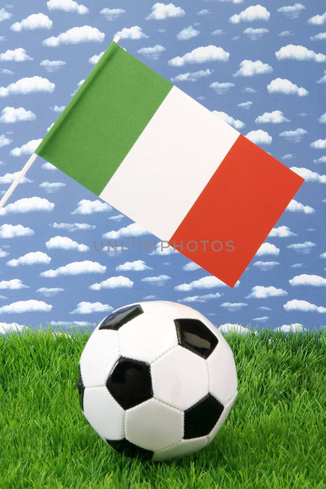 Soccerball on grass with italian national flag over sky background