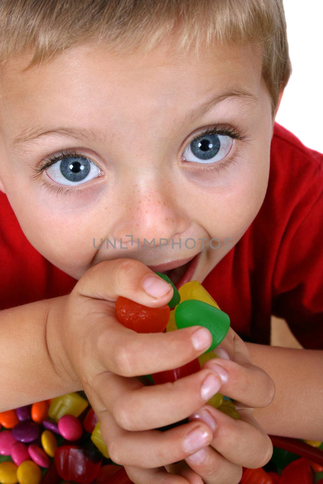 Young blond boy eating a hand full of candy