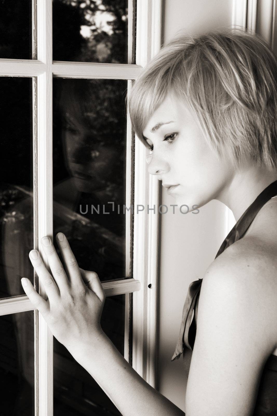 Beautiful blond female leaning against a door, expressing sadness and loneliness