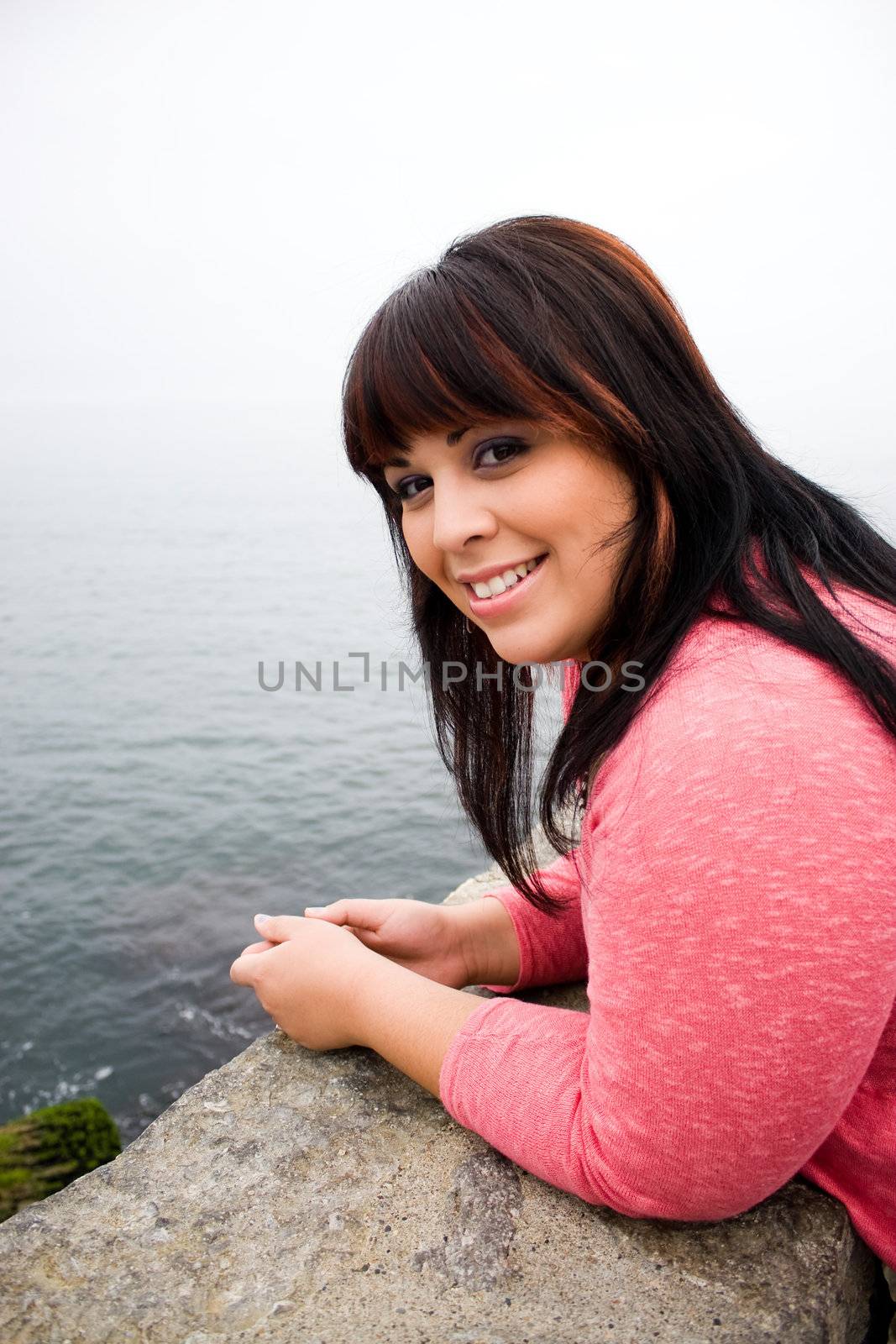 A young hispanic woman with red highlights in her hair by the sea shore in Newport Rhode Island.