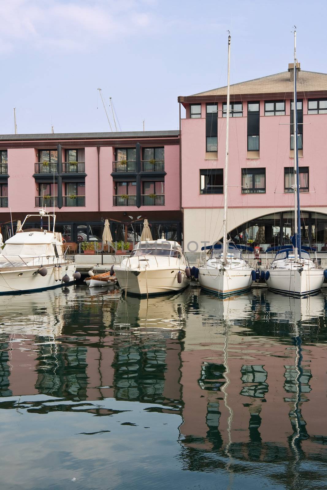 Sailing boats moored in Genova harbor with water reflections