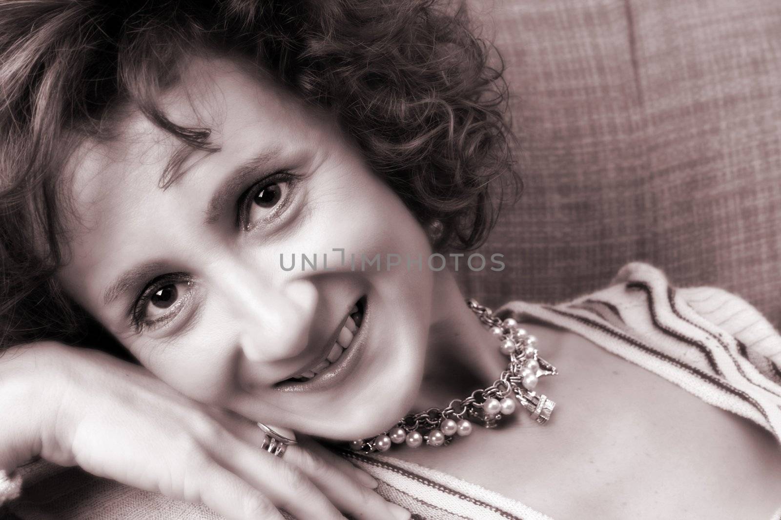 Mature female posing on the sofa wearing jewelery